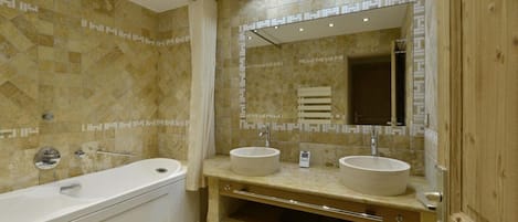 A bathroom with a bathtub, two sinks, a mirror, and a shower.