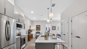 A modern kitchen with stainless steel appliances, a central island, and a dining area. - The Jardin Lavender Suite | Near Downtown (Savannah)
