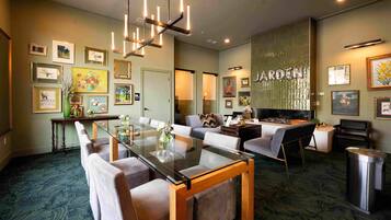 Una sala de estar moderna con una mesa de comedor de cristal, sofás, un televisor y obras de arte en las paredes.