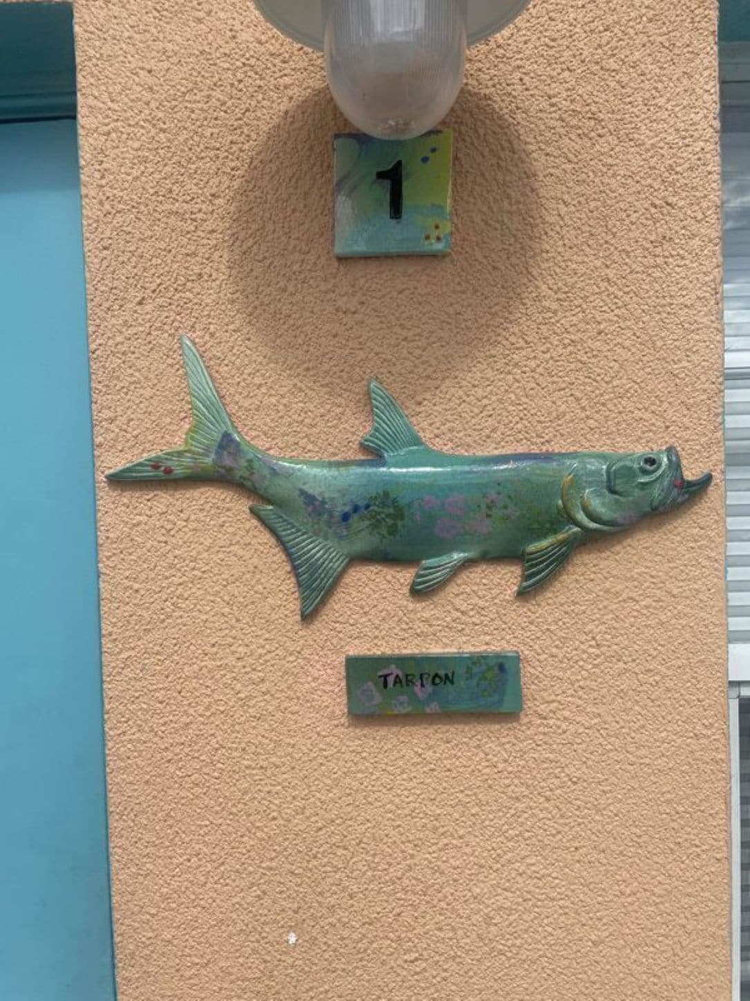 A fish sculpture with a label 'TARFON' on a textured wall.