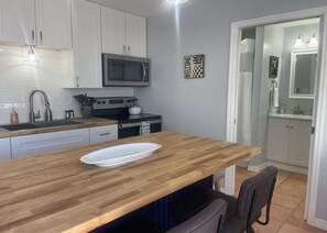 A modern kitchen with white cabinets, a microwave, and a wooden countertop. - 1 bedroom apartment with AC Pompano Suite (Saint James City)