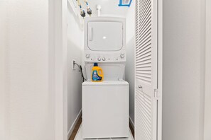 A laundry room with a washing machine, a dryer, and a bottle of detergent. - Stylish Haven with Scenic DTLA Views & Parking - Walking to Little Tokyo (Los Angeles)