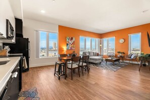 Un apartamento moderno con cocina, comedor y sala de estar, grandes ventanales y vistas a la ciudad.