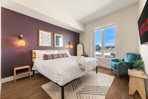 A modern bedroom with a large bed, a view of the city, and a Netflix sign on the wall. - Stylish Haven with Scenic DTLA Views & Parking - Walking to Little Tokyo (Los Angeles)