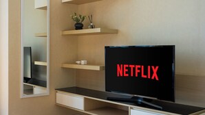 A modern room with a television displaying 'NETFLIX,' a mirror, and built-in shelves with decorative items. - Skyline View · Pool, Gym, Fast Wi-Fi (Watthana)