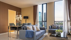 A modern living room with a sofa, a coffee table, and a dining area with a table and chairs. - Skyline View · Pool, Gym, Fast Wi-Fi (Watthana)