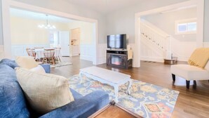 A spacious living room with a sofa, a flat-screen TV, a fireplace, and a staircase. - Historic Home Downtown Gary Near BP/80/94 Hospital (Gary)