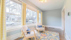 A room with two rocking chairs, a patterned rug, a large window with curtains, and a ceiling light fixture. - Historic Home Downtown Gary Near BP/80/94 Hospital (Gary)