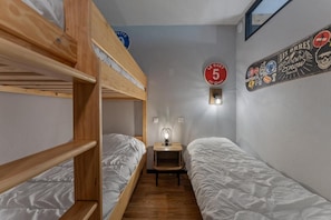 A bunk bed room with a small table and wall decorations. - 40m from ski slopes, Ground floor, fitness, swimming pool, sauna, balcony, tv, ski locker, 35m² (Les Orres)
