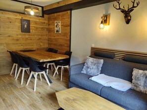 A wooden interior with a dining table, chairs, a sofa, and a mounted deer head. - 40m from ski slopes, Ground floor, fitness, swimming pool, sauna, balcony, tv, ski locker, 35m² (Les Orres)