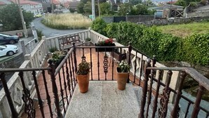 Una escala amb barana metàl·lica, plantes en testos i vista a una zona residencial amb cases i un carrer.