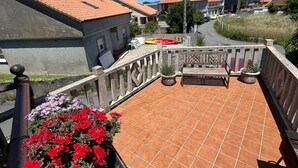 Una terrassa al terrat amb sòl de rajola, barana metàl·lica i plantes en testos.