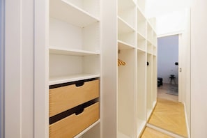 Ein begehbarer Kleiderschrank mit offenen Regalen, einer Holzkassette und einem Spiegel.