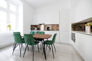 Eine moderne Küche mit weißen Schränken, einem Holztisch und grünen Stühlen.