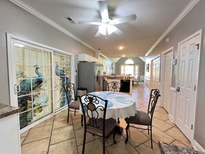 A dining area with a round table, chairs, a ceiling fan, and a peacock-themed glass door. - Spacious 4BR Family Retreat with Fenced Yard & BBQ (Myrtle Beach)