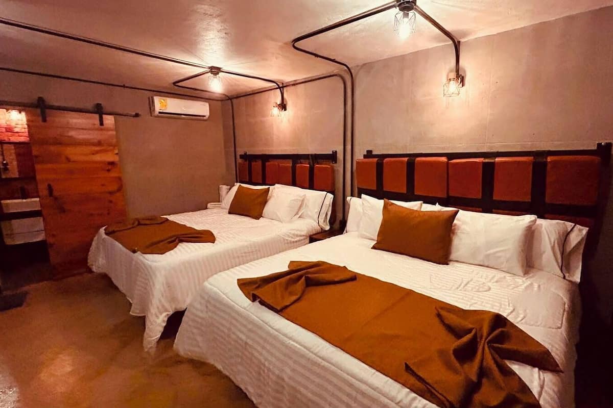 Ein Hotelzimmer mit zwei Betten, Holzwänden und einem Kamin aus Ziegelsteinen.