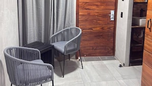 Ein Zimmer mit Holztür, grauen Vorhängen und zwei grauen Stühlen.