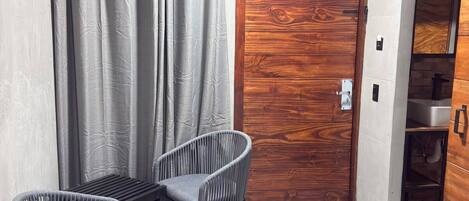 Une pièce avec une porte en bois, des rideaux gris et deux chaises grises.