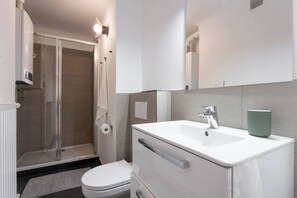 Ein modernes Badezimmer mit Dusche, Toilette, Waschbecken und Handtuchhalter.