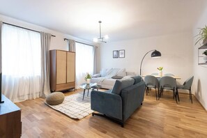 Ein modernes Wohnzimmer mit einer Couch, einem Esstisch mit Stühlen, einer Lampe und einem Kleiderschrank.