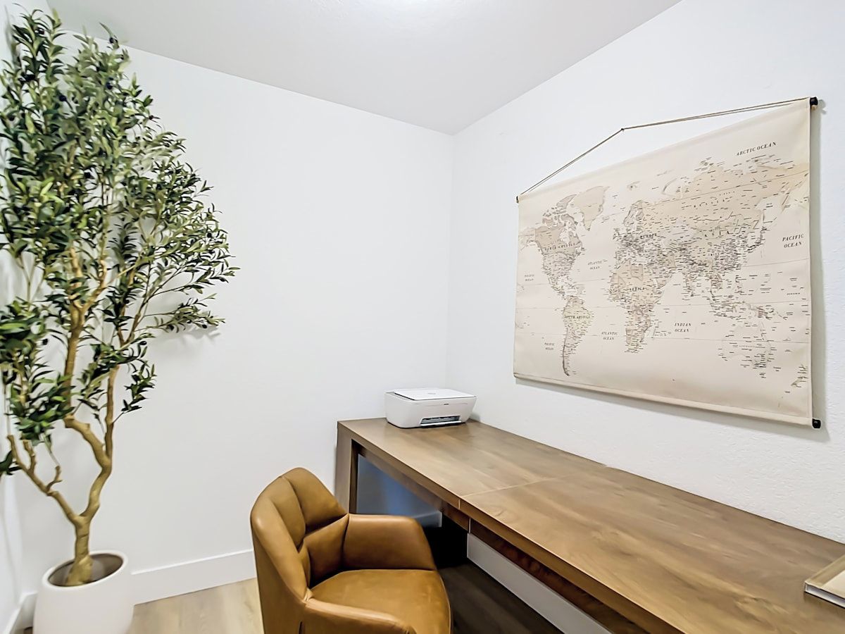 Une pièce comprenant un bureau, une chaise, une imprimante et une carte du monde accrochée au mur.