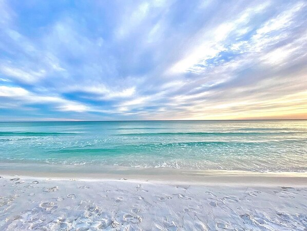 Ein Strand mit Fußabdrücken im Sand und einem klaren Himmel.