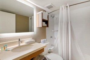 Ein Badezimmer mit Waschbecken, Spiegel, Toilette und Duschvorhang.