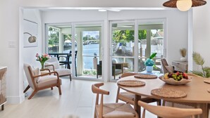 A spacious dining area with a view of the water, wooden furniture, and a potted plant. - Waterfront 3 King Suites - Dock + Pool Near Beach - Paddleboards Included (Fort Lauderdale)