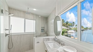 A modern bathroom with a large window, a shower, a sink, and a toilet. - Waterfront 3 King Suites - Dock + Pool Near Beach - Paddleboards Included (Fort Lauderdale)