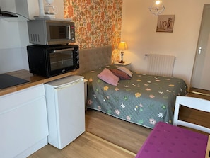 Une chambre de taille réduite comprenant un lit, un four à micro-ondes, un petit réfrigérateur et une table avec une chaise.