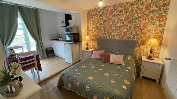 Ein Schlafzimmer mit Bett, Nachttischlampen, einem Schreibtisch und einer Küchenzeile.