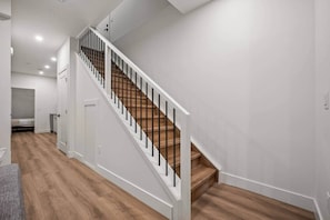 A staircase with white railings and wooden steps, leading to a room with a door and a small closet. - The Canopy - Steps to Ctrain and 17th ave (Calgary)
