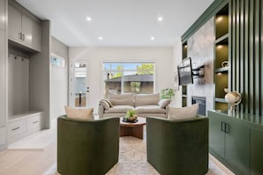 A modern living room with a sofa set, a coffee table, and a TV mounted on the wall. - The Olive - Luxury, 5 min 2 DT, Steps From Ctrain (Calgary)