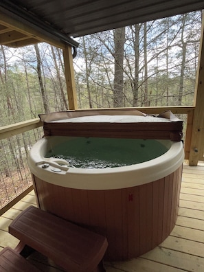 Ein Whirlpool auf einer Holzterrasse mit Blick auf Bäume.