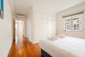 Ein Schlafzimmer mit einem Bett, einem weißen Kleiderschrank und einem Fenster mit Blick.