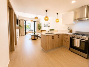Een moderne keuken met houten kastjes, een gasfornuis en hangende lampen.