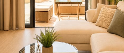 A modern living room with a sofa, a glass coffee table, and a view of an outdoor patio with a white umbrella.