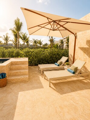 A poolside area with lounge chairs, a large umbrella, and steps leading to a hot tub. - 2BR Crystal Lagoon Retreat Puntacana Prive Pool (Punta Cana)