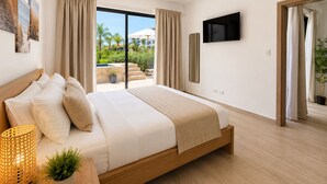 A modern hotel room with a large bed, a TV, and a view of a pool and greenery. - 2BR Crystal Lagoon Retreat Puntacana Prive Pool (Punta Cana)