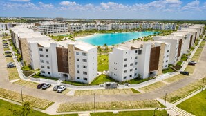 A modern hotel complex with multiple buildings, a central swimming pool, and a well-maintained surrounding area. - 2BR Crystal Lagoon Retreat Puntacana Prive Pool (Punta Cana)