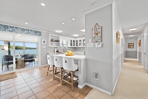 A modern kitchen with a large island, bar stools, and a view of the outdoors. - NEW! Hot Tub, Large Dock, Sunset Views | Sleeps 11 (Mooresville)