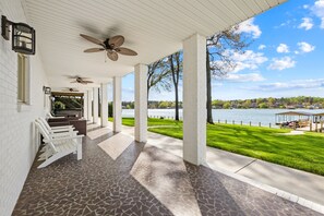 A covered patio with a view of a lake, white brick walls, and a pergola with seating. - NEW! Hot Tub, Large Dock, Sunset Views | Sleeps 11 (Mooresville)