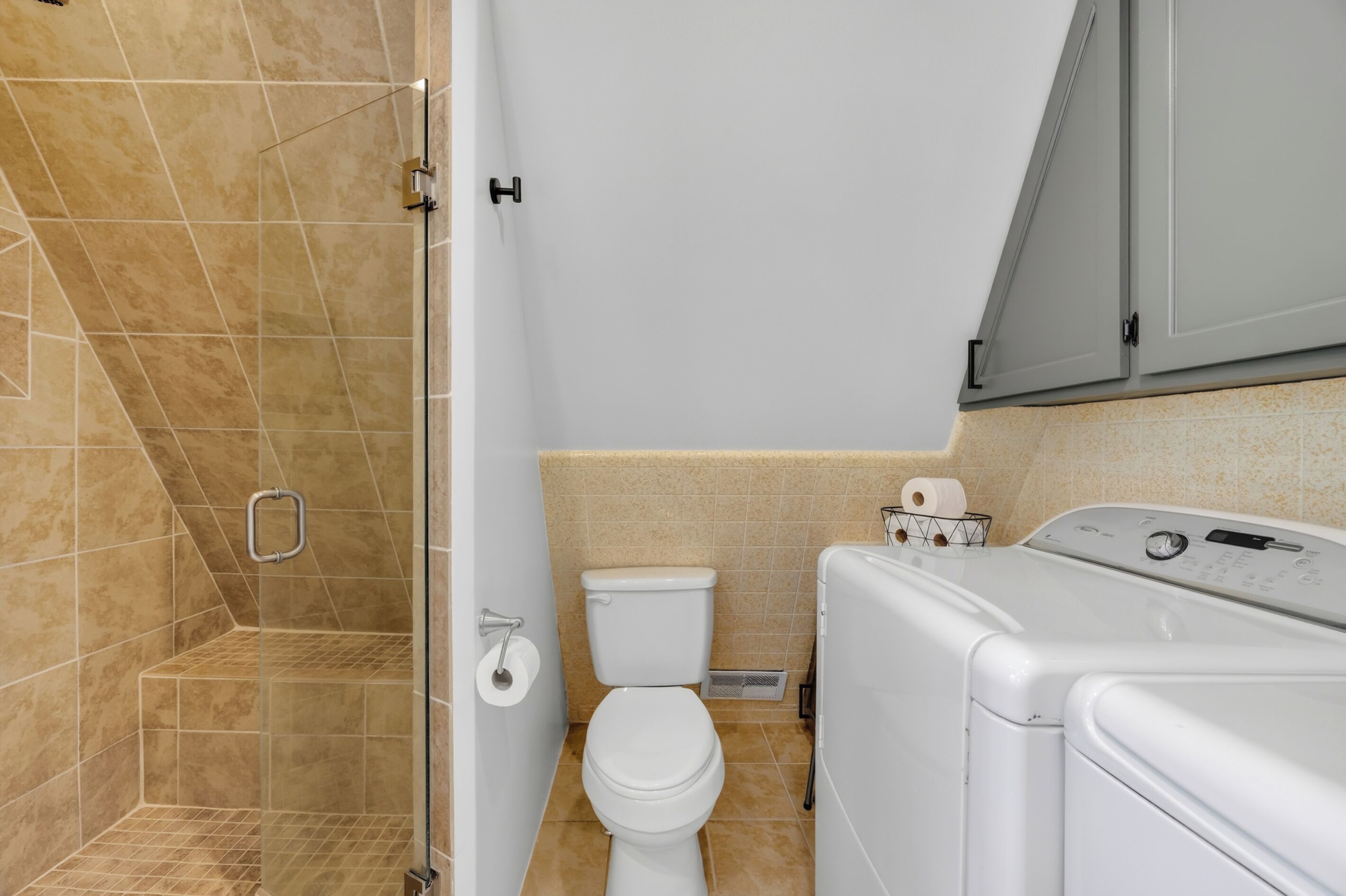 Un baño con ducha, inodoro y lavadora.