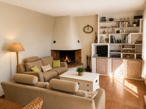 A living room with a fireplace, sofa, coffee table, and a bookshelf. - A charming vacation home, nestled in a quiet spot at the foot of Mont Ventoux! (Mazan)