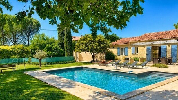 Ein Swimmingpool mit Liegestühlen, eine Terrasse und ein Gebäude mit einem Ziegeldach.