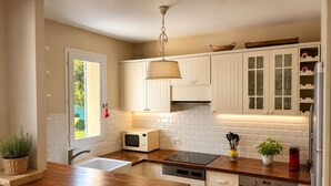 Eine moderne Küche mit weißen Schränken, einer Holz Arbeitsplatte, einer eingebauten Mikrowelle, einem Geschirrspüler und einem Backofen.
