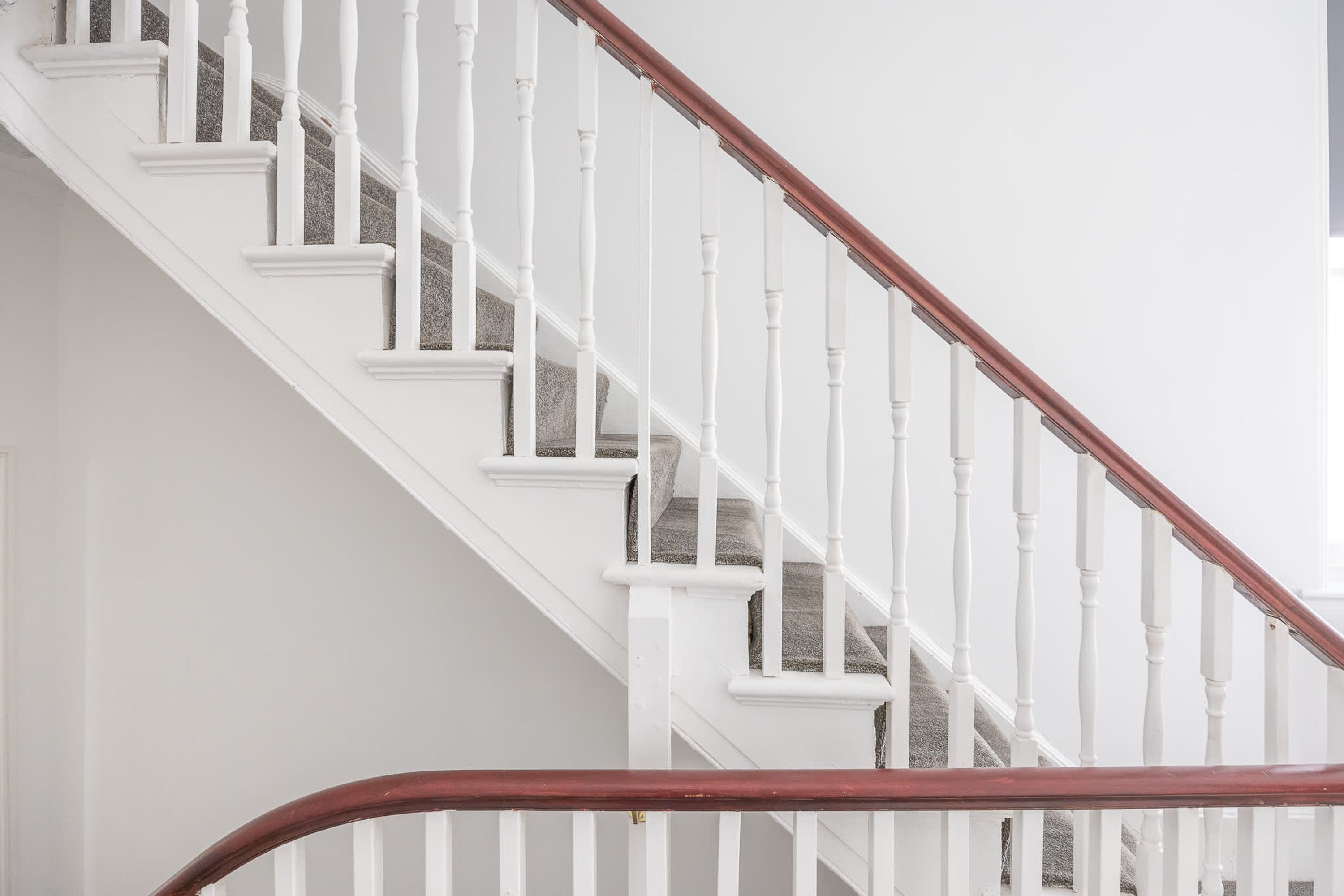 A staircase with white balusters and a wooden handrail.