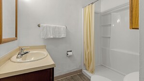 Un baño con lavamanos, espejo, toallero, inodoro y cortina de ducha.