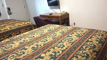 A hotel room with two beds, a desk, a chair, and a television.