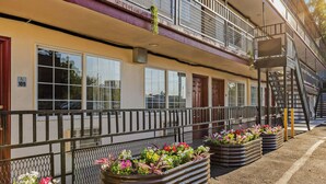 Un edificio de varios pisos con balcón, señal de accesibilidad para sillas de ruedas y escalera de incendios.